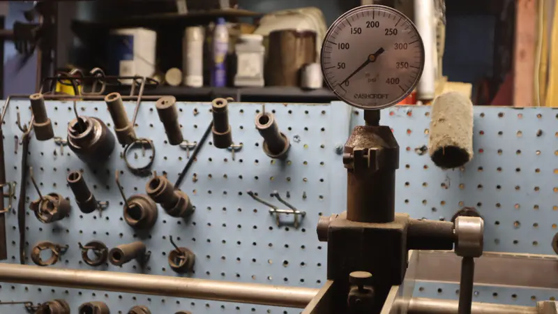 The pressure test rig in the machine shop: a big gauge over a pegboard of fittings